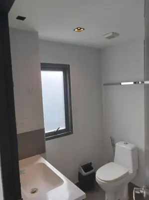 a white bathroom with a toilet and a window at Large Corner Apartment 1BR - NV-207 in Chalong