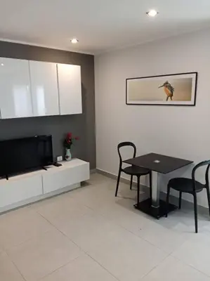 a living room with a table and a television at Large Corner Apartment 1BR - NV-207 in Chalong