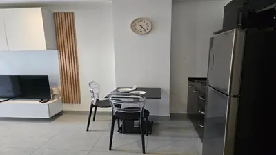 a kitchen with a table and chairs and a clock on the wall at Bright & Breezy -1BR T1-211 in Chalong