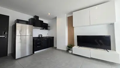a kitchen with white cabinets and a large television at Big Buddha View Apt-1BR T1-306 in Chalong