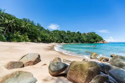 a beach with rocks in the sand and the ocean at Patong Station House in Patong Beach