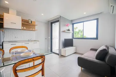 a kitchen and living room with a table and a couch at Modern & Stylish Apartment-2BR - NV-518 in Phuket Town