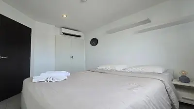 a white bedroom with a bed with white sheets at Tranquil Tide 1 BR T1-605 in Chalong