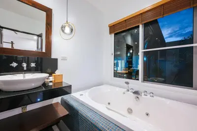 a bathroom with a tub and a sink and a window at Tranquil 3 Bedroom Garden Pool Villa in Laguna Phuket