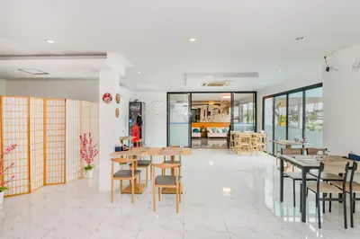a dining room with wooden tables and chairs at De Blue Sea Rawai Hotel in Ban Saiyuan (1)