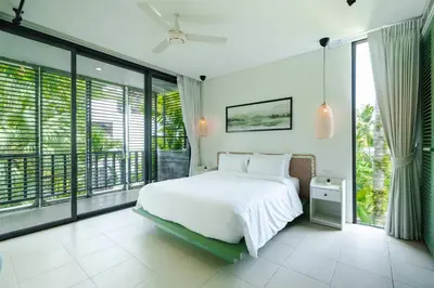 a bedroom with a white bed and large windows at Stylish Penthouse at Bangtao Beach in Surin Beach