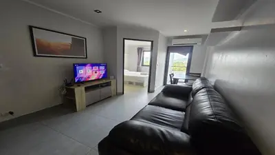 a living room with a leather couch and a television at The Chalong Pearl 1BR T1-703 in Phuket Town