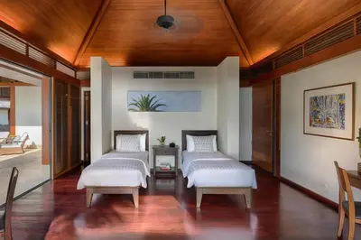 two beds in a room with wooden ceilings at Villa Ananda at Jivana Beach Villas in Pilai Beach