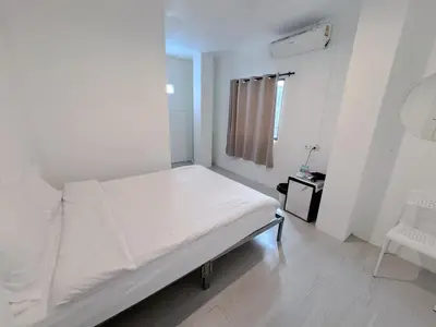 a white bedroom with a bed and a chair at XX BAO Pathong Beach เบา ป่าตอง บีช in Patong Beach