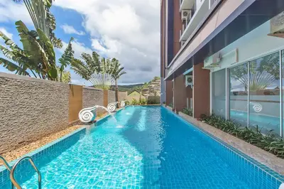 a swimming pool in the side of a building at Cosy 1 bedroom Chic condo in Karon Beach