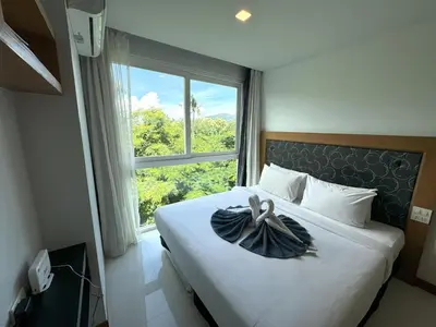 a bedroom with a bed with a large window at Cozy apartment at peaceful Rawai Condo in Rawai Beach