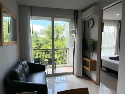 a living room with a couch and a balcony at Cozy apartment at peaceful Rawai Condo in Rawai Beach