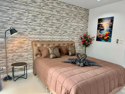 a bedroom with a large bed in front of a brick wall at TN KAMALA Room For Rent in Kamala Beach