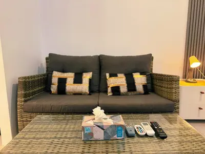 a living room with a couch and remotes on a table at Ground Floor Zen Space Kamala in Kamala Beach