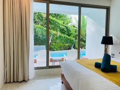a bedroom with a bed and a view of a pool at Oceana Kamala in Kamala Beach
