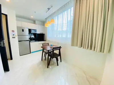 a dining room with a table and a kitchen at Oceana Kamala in Kamala Beach