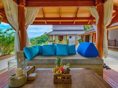 an outdoor patio with blue pillows and a table at Baan Surin Sawan in Surin Beach
