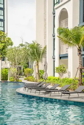 a swimming pool with chaise lounge chairs and palm trees at Title Halo Life in Yellow 40m2 King Bed Pool in Nai Yang Beach