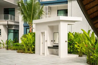 a white building with a palm tree in front of it at Title Halo Life in Yellow 40m2 King Bed Pool in Nai Yang Beach