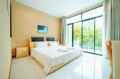 a bedroom with a large bed and a large window at Rich Pool Villa Phang Nga in Khok Kloi