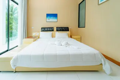 a large white bed in a room with a large window at Rich Pool Villa Phang Nga in Khok Kloi