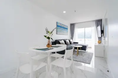 a white living room with a table and a couch at Patong Tower Brand 1-Bedroom apartment mountain view , Near Beach in Patong Beach