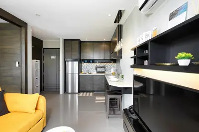 a kitchen with black cabinets and a yellow couch at Kamala CityGate Apartments in Kamala Beach