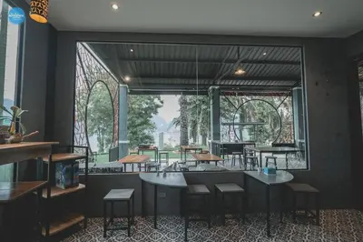 a restaurant with tables and chairs and a large window at Bulan Anda Resort in Ban Hua Laem