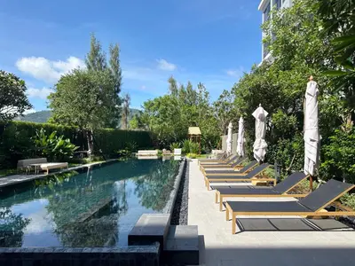 a row of lounge chairs and umbrellas next to a swimming pool at Laguna Lakeside in Bang Tao Beach