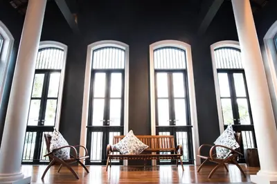 a room with four windows with chairs and a table at Little Nyonya Hotel in Phuket Town