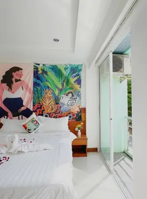 a bedroom with a white bed with a painting on the wall at Lanting House Phuket in Patong Beach