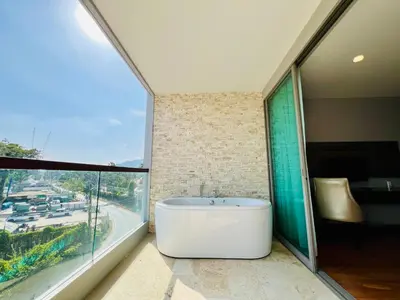 a bath tub in a bathroom with a large window at The Regent Bangtao by RESAVA in Bang Tao Beach