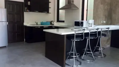 a kitchen with a white counter and bar stools at Villa Patong in Patong Beach