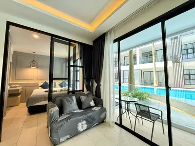 a living room with a couch and a bedroom at Poolside 1 Bedroom Apartment by Renttini in Surin Beach
