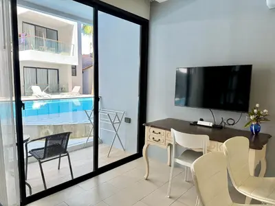 a living room with a television and a table and chairs at Poolside 1 Bedroom Apartment by Renttini in Surin Beach