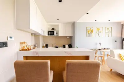 a kitchen with white cabinets and a table and chairs at Apart Close to the Beach Sea view in Rawai Beach