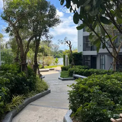 a walkway through a park with trees and a building at Cassia Phuket laguna 1 BDR in Laguna Phuket