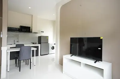a living room with a large television and a kitchen at Hommory Residence - East Chalong in Phuket Town