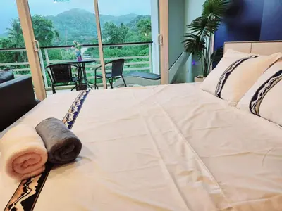 a bedroom with a bed with a view of the mountains at Veloche Karon palm in Phuket Town