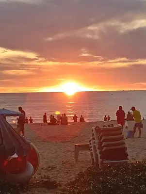 a group of people on the beach at sunset at Veloche Karon palm in Phuket Town