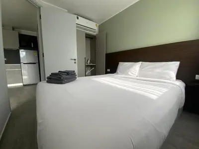 a large white bed in a room with a kitchen at CondoHotel Chalong in Ban Klang