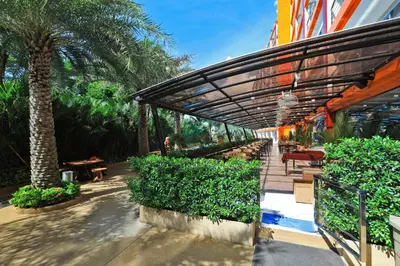 acovered walkway with a palm tree and tables and benches at Mai Khao Beach Condo by Capital Pro in Mai Khao Beach