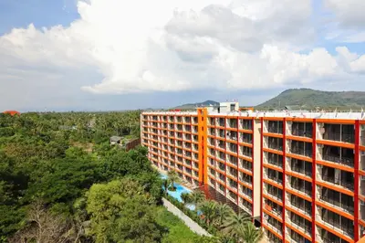 an orange and white building in the middle of a forest at Mai Khao Beach Condo by Capital Pro in Mai Khao Beach
