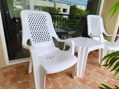 three white chairs and a table on a balcony at Baan Thawin in Patong Beach