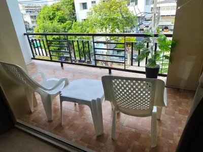 a balcony with two chairs and a table and a window at Baan Thawin in Patong Beach