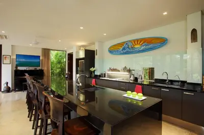 a kitchen with a counter with a sink and some chairs at 23 - Seaside Villa Retreat in Phuket Town
