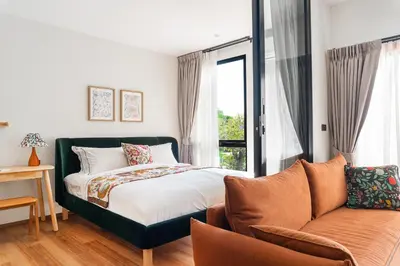 a bedroom with a bed and a couch and a window at Title Halo Time for Jungle 40m2 King Bed Pool in Nai Yang Beach