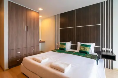 a bedroom with a large white bed with wooden cabinets at Golden Manora Hotel Bangtao Beach Phuket in Bang Tao Beach