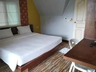a bedroom with a white bed with a table and a chair at Mountain View Resort in Nai Yang Beach