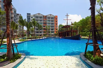 a large swimming pool with palm trees and buildings at 1 BR apartment in Title Naiyang in Nai Yang Beach
